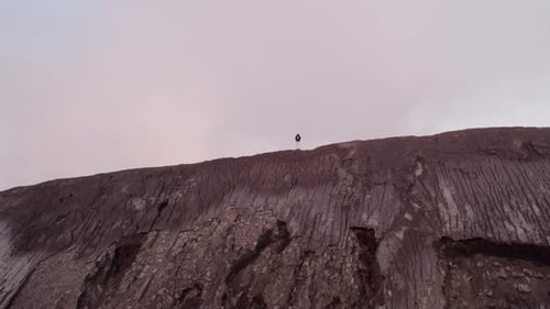 Aerial view of smoking volcano with man walking on summit, Indonesia.