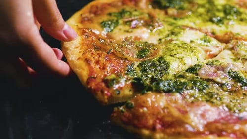 Female Hand Taking a Slice of Italian Pizza and Putting It on a Plate Close Up