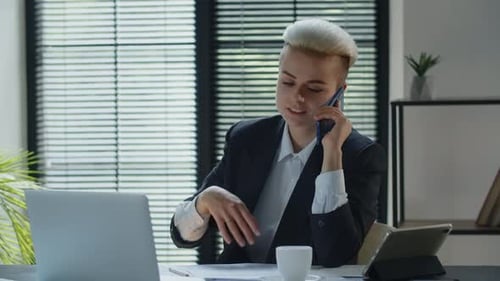 Young Adult Working on Laptop Talking on Phone