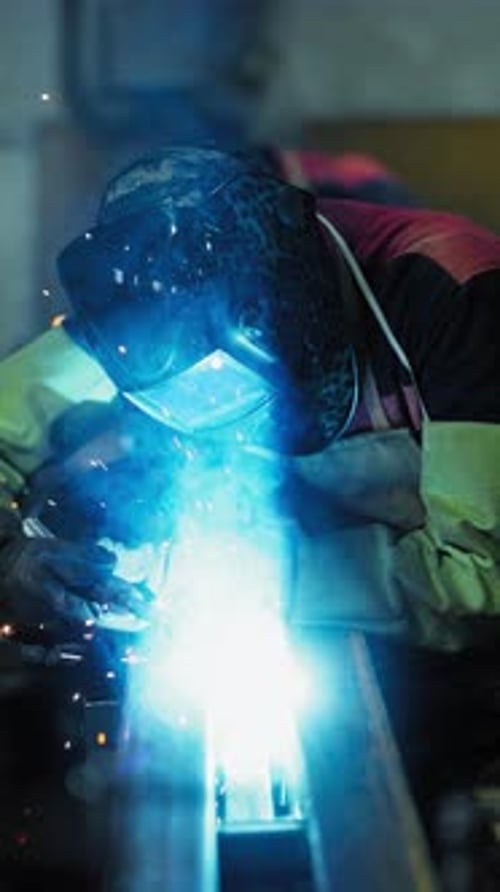 Soudeur professionnel travaillant dans un atelier d'usine avec un technicien masculin soudant