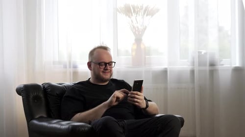 young man happy about scrolling his phone