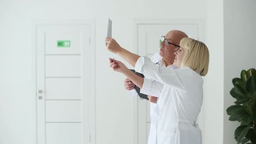 Senior man and woman doctors in white uniform examines x-ray in the clinic