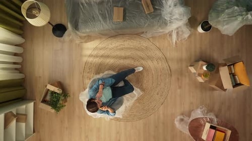 Top View of Apartment Living Room Woman Sitting on the Chair in New Apartment Talking on Smartphone