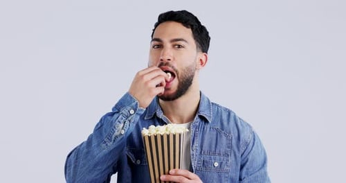 Popcorn, man face and watching tv or movie with snack, theater food and streaming in studio