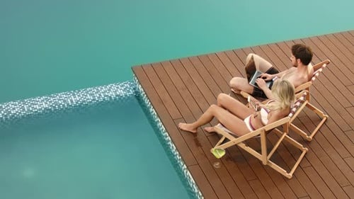 Couple Relaxing and Using Laptop Near Pool