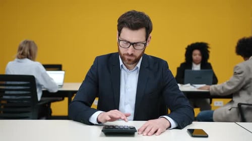 Portrait of a Bearded Man in Glasses Analyzing His Profit in Modern Office Space