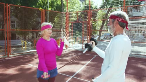 Active Seniors Doing Bicep Curls Outdoors