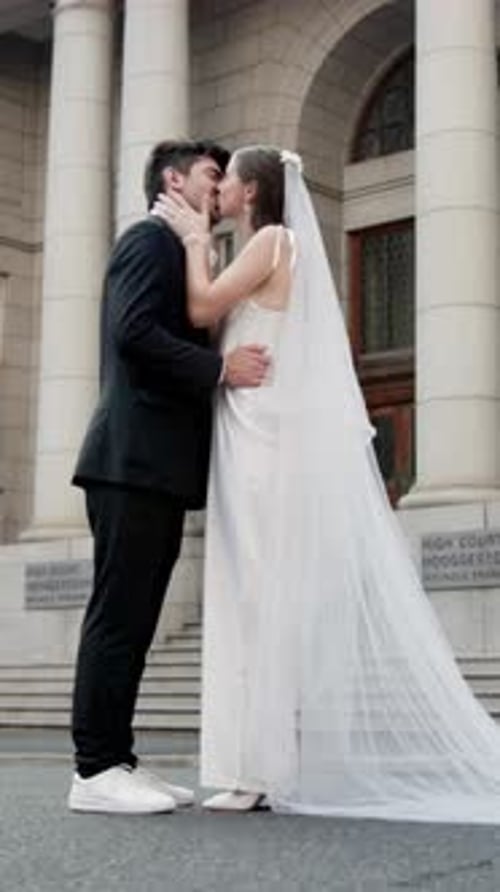 Happy couple, wedding and kiss with love in city for marriage, intimacy or romantic affection
