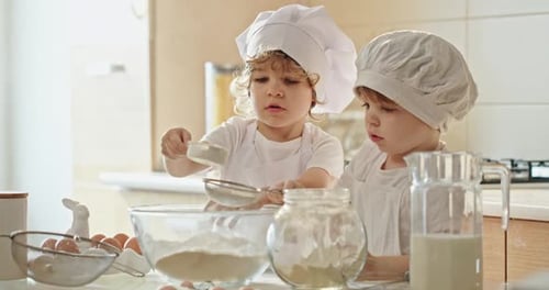 Two Toddlers in Chef Hats are Cooking in a Kitchen