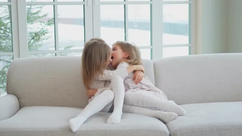 Two Girls Laughing and Hugging on a Couch