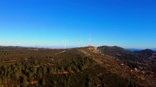 Aerial drone footage of a wind turbines on mountain ridges generating renewable energy.