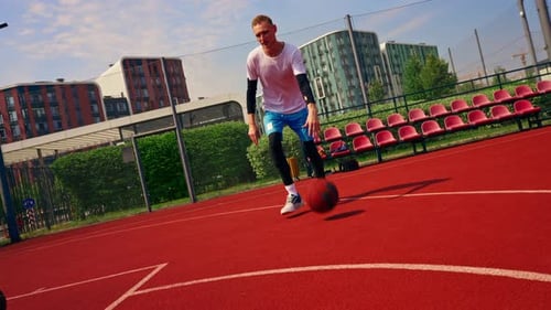 a Tall guy basketball player with the ball shows his dribbling skills during practice