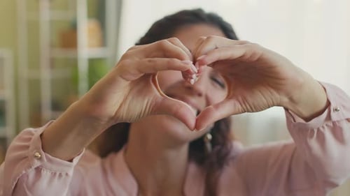 Smiling Woman Making Heart Shape with Hands