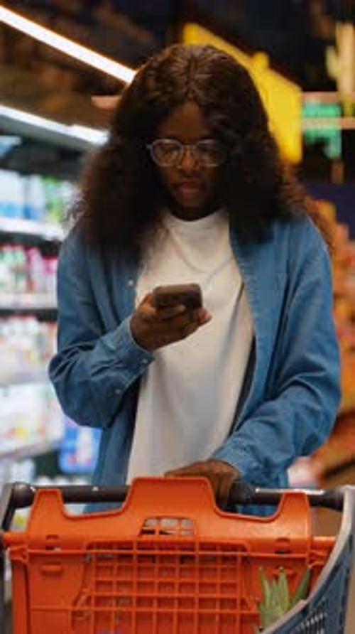 African American Woman Using Smartphone While Grocery Shopping