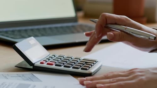 Woman Calculates Finances at Desk Close Up