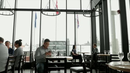 Businessman texting on smart phone at restaurant table connecting with technology