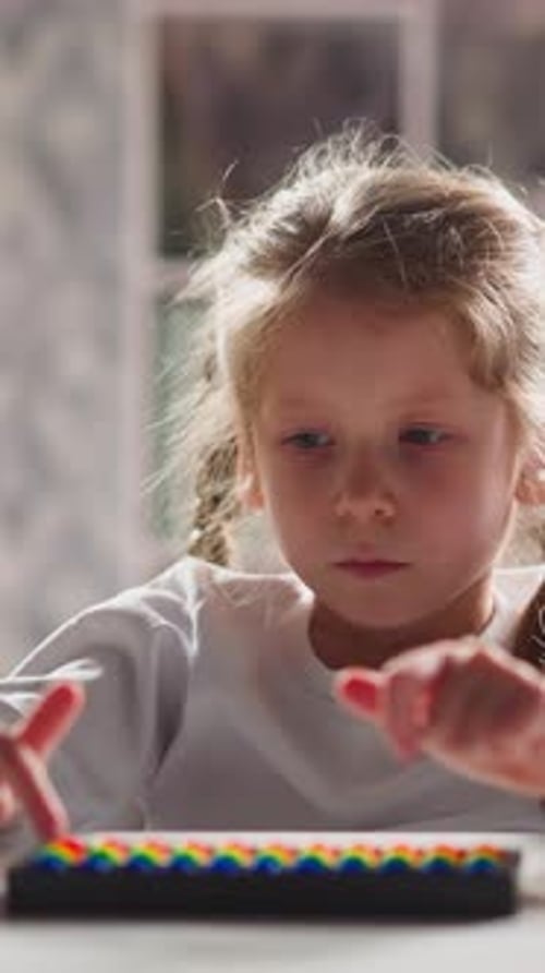 Una niña molesta juega con Abacus en Mental Arithmetics