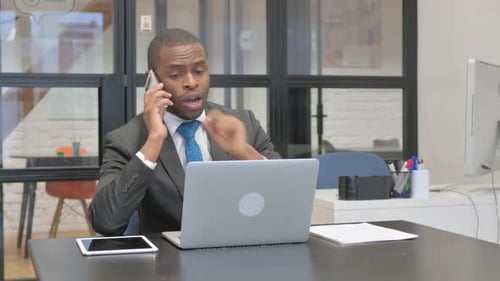 Man Talking on Phone Working at Computer