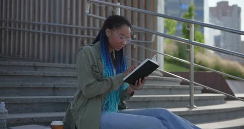 Young Woman Reading on Urban Steps