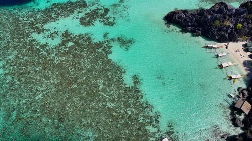 Imágenes de Zumbido de arriba hacia abajo de una playa con barcos en la isla de Coron en Filipinas.
