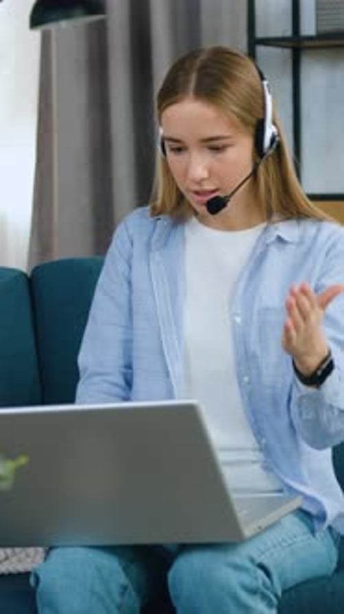 Woman with Headset Video Conferencing on Laptop at Home
