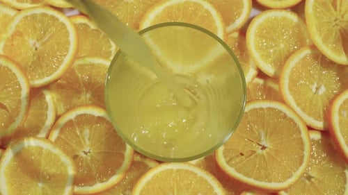 Orange juice poured into glass surrounded by oranges