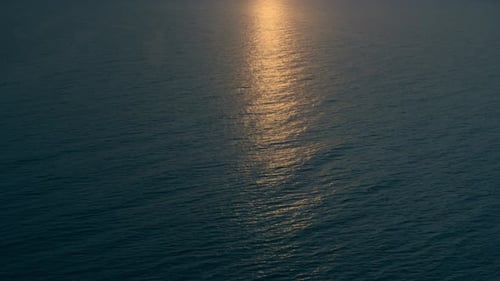 Golden sunlight reflecting on the ocean surface at sunrise aerial view