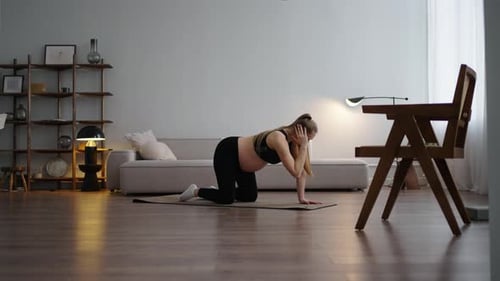 Femme enceinte caucasienne faisant des étirements pour soulager les douleurs de la colonne vertébrale à la maison, au fitness et pendant la grossesse