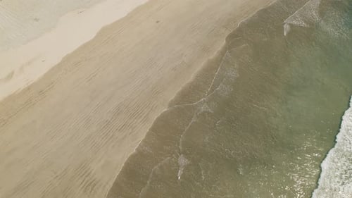 Aerial top view of turquoise waves approaching sandy coast at Ostional beach in Costa Rica
