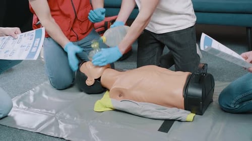 Adults Learn CPR Using Mannequin for First Aid