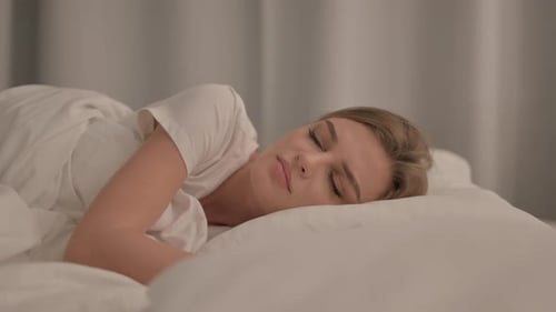 Vue latérale de la jeune femme qui tousse en position couchée dans son lit