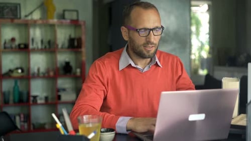 Man Working at Desk with Laptop in Home