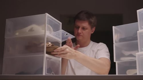Man Organizing Shoes in Clear Plastic Containers