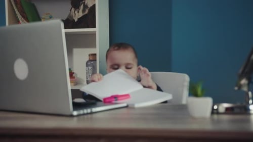 Baby Sits at Desk with Laptop and Notebook