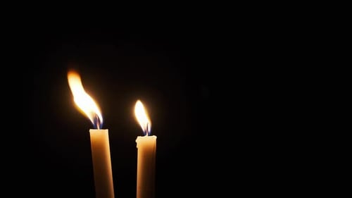 Deux bougies brûlent sur fond noir