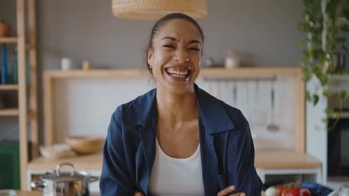 Happy young latin woman smiling at camera in her kitchen