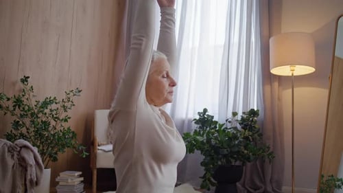 Senior Woman Holds Prayer Hands Near Chest Closing Eyes in Studio