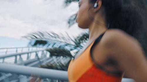 Fitness, earphones and woman in city running while streaming motivation music, radio or podcast