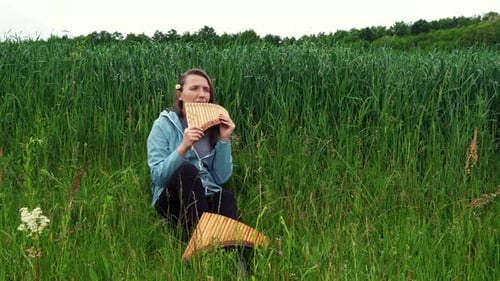 Una joven toca la panflauta en la naturaleza