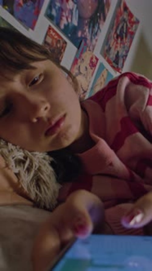 Tired Asian Girl Chats in Messenger Using Phone Lies in Bed