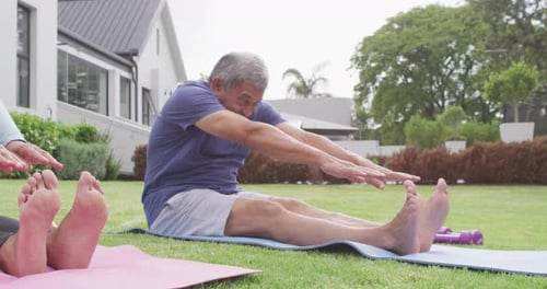 Happy senior diverse couple practicing yoga in garden