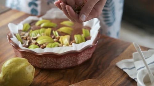 close-up woman prepares an open pie, spreads nuts on top