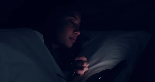 Una mujer duerme sola en una cama por la noche.