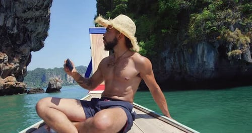 Man on boat in tropics takes photos on phone
