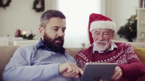 A Senior Father and Adult Son with Tablet Sitting on a Sofa
