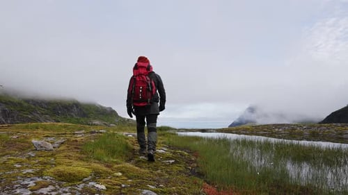 Solo Traveler with a Big Red Backpack Walks Along the Tops of the Mountains Norway Near Munken and