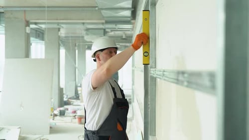 Construction Worker Checks Level of a Wall