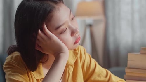Close Up Of Young Asian Female Being Bored To Read The Books While Studying At Home