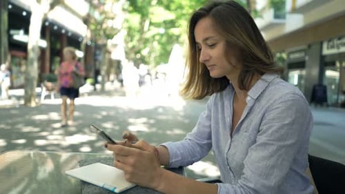 Young Businesswoman Texting on Smartphone Sitting in Cafe in City Adult