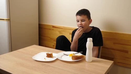 Boy Having a Snack at Wooden Table Indoors
